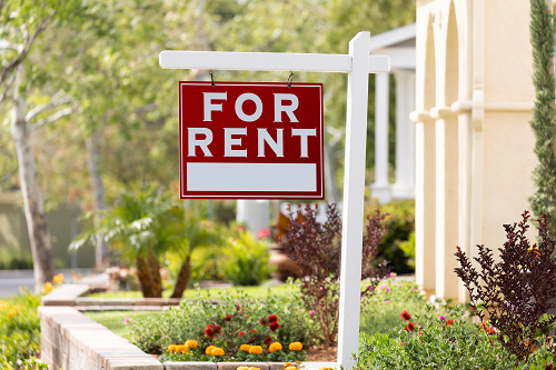 A red "for rent" sign outside of a house.