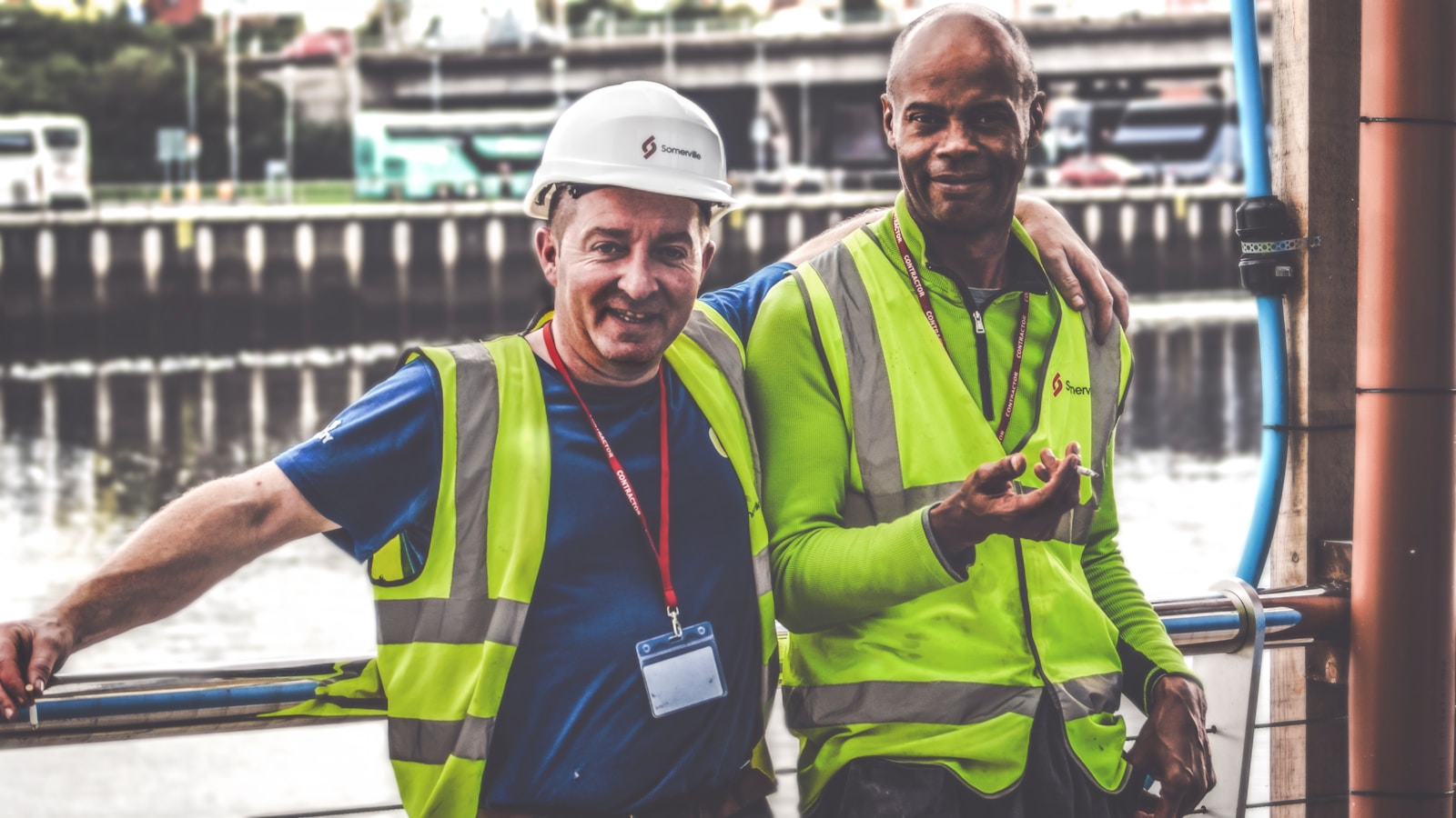 selective focus photography of two men with workers' compensation standing side by side wearing green reflective vests